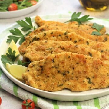 Baled breaded cjoclem cutlets plated with salad bowl next to them.