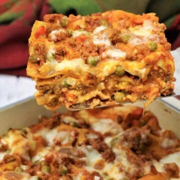 Wedge of Sicilian lasagna with ragu with peas served with spatula.