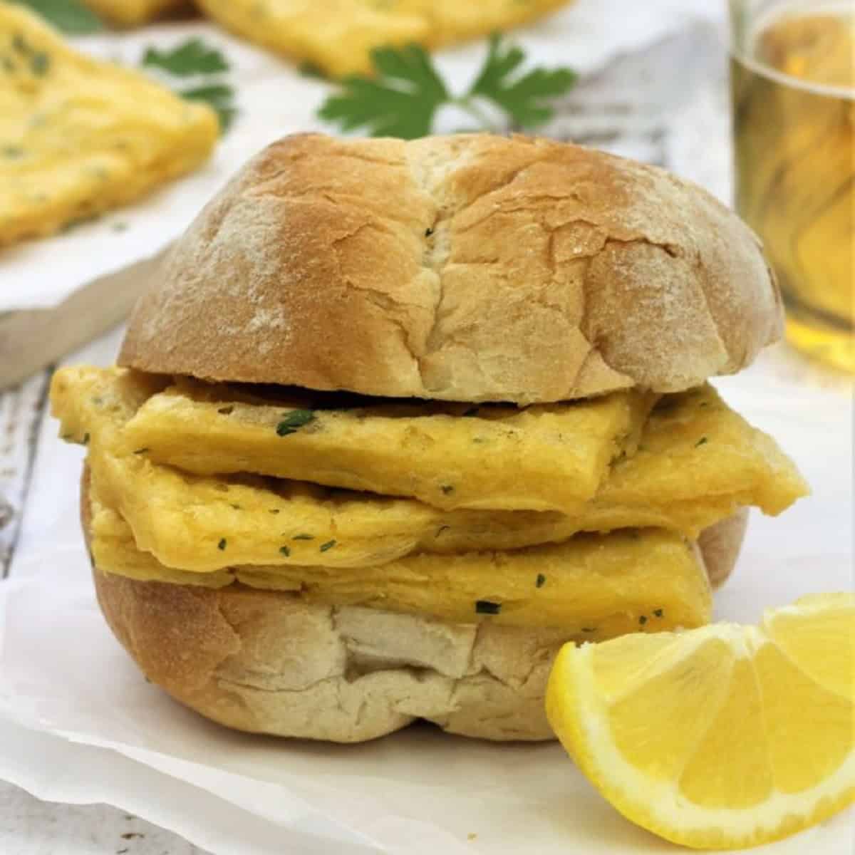 Sicilian chickpea fritters in a panino next to lemon wedge.