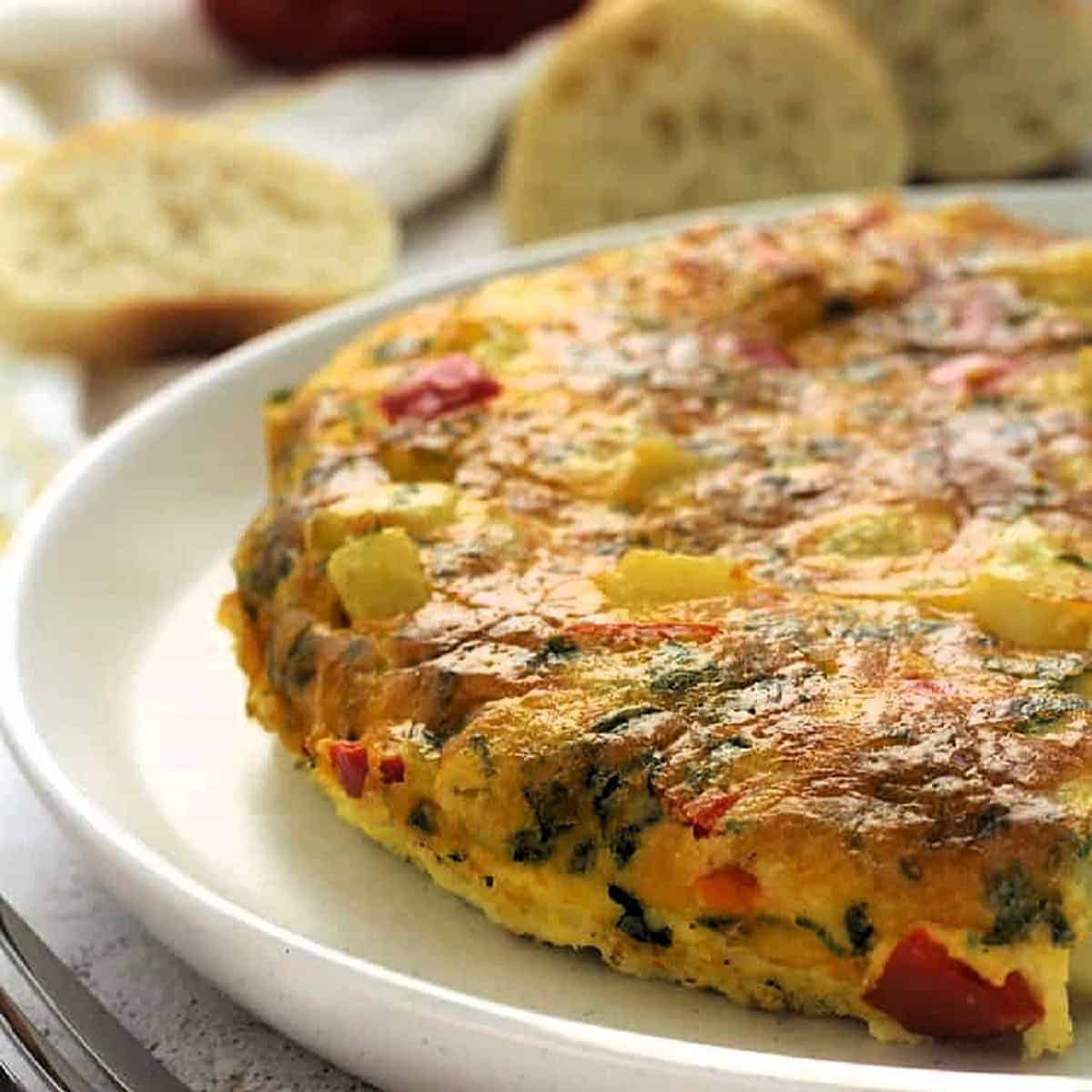 Italian baked frittata with potato and red pepper on plate.