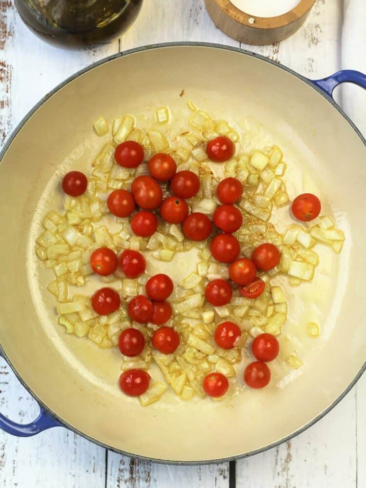 Sautéed onion and cherry tomatoes in sauce pan for swordfish recipe.
