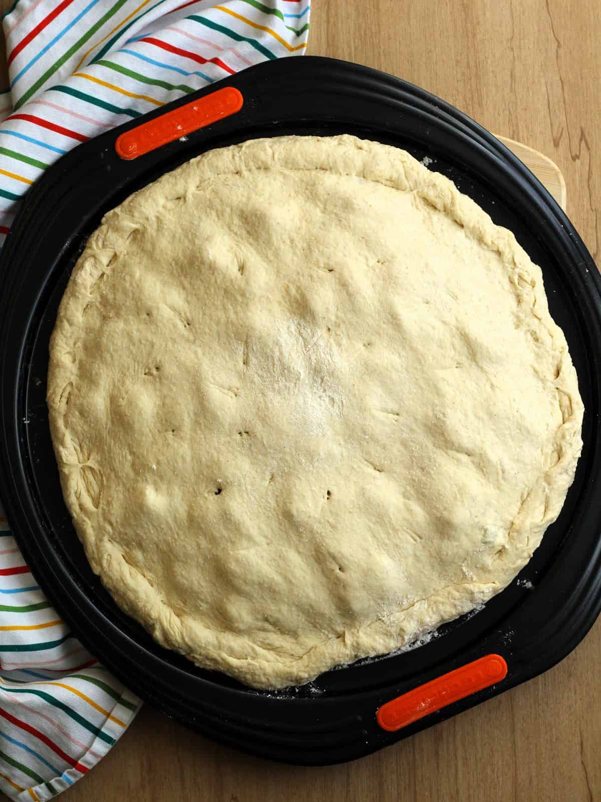 Double crust scacciata Messinese filled with escarole on pizza pan.