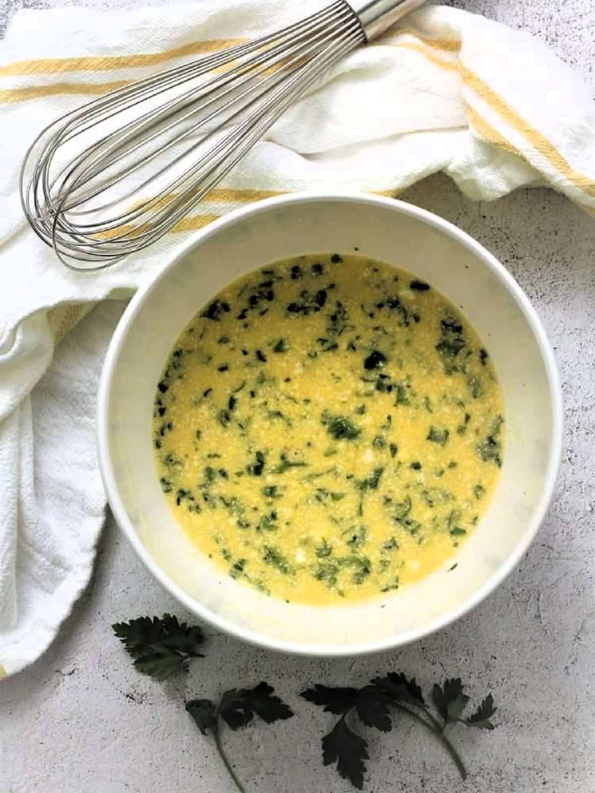 Bowl with beaten eggs, Parmigiano cheese and parsley for frittata.