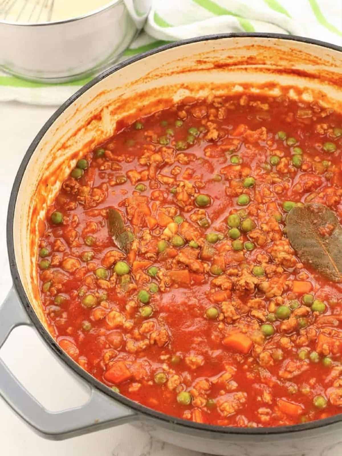 Ragu with peas simmering in skillet.