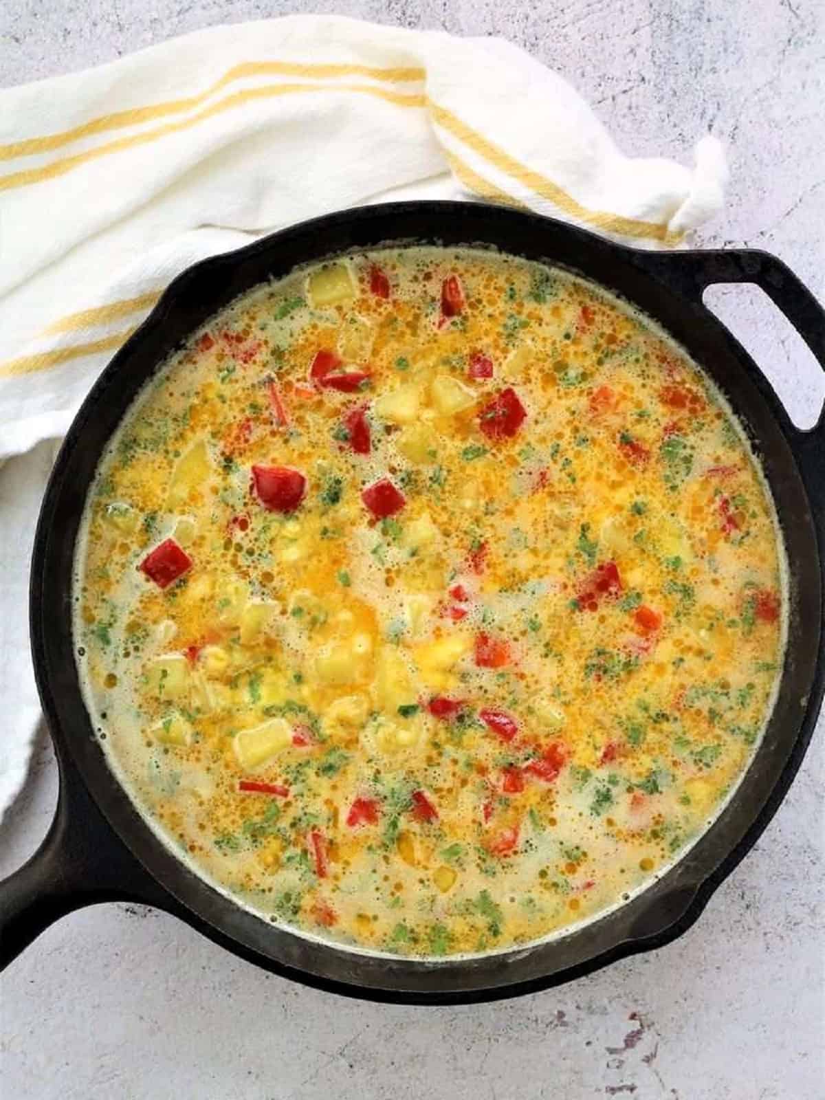 Potato and red pepper frittata mixture in cast iron skillet.