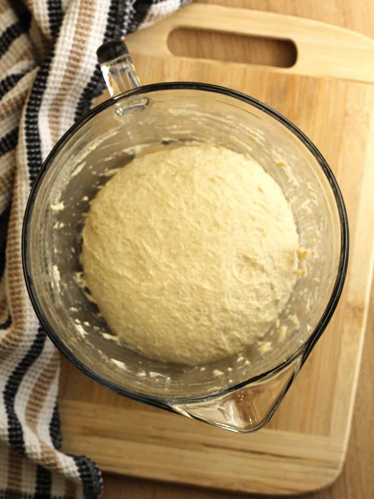 Proofed no-knead dough shaped into a ball in bowl.