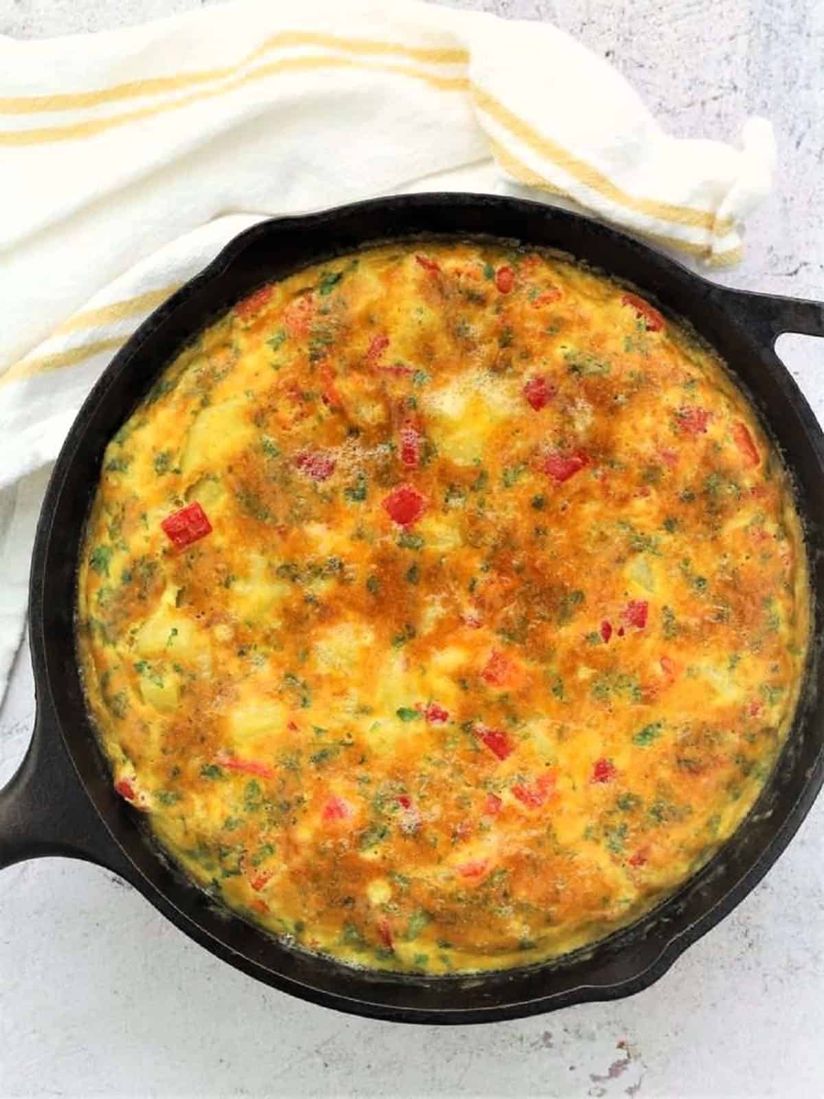 Oven broiled potato and red pepper frittata in cast iron skillet.