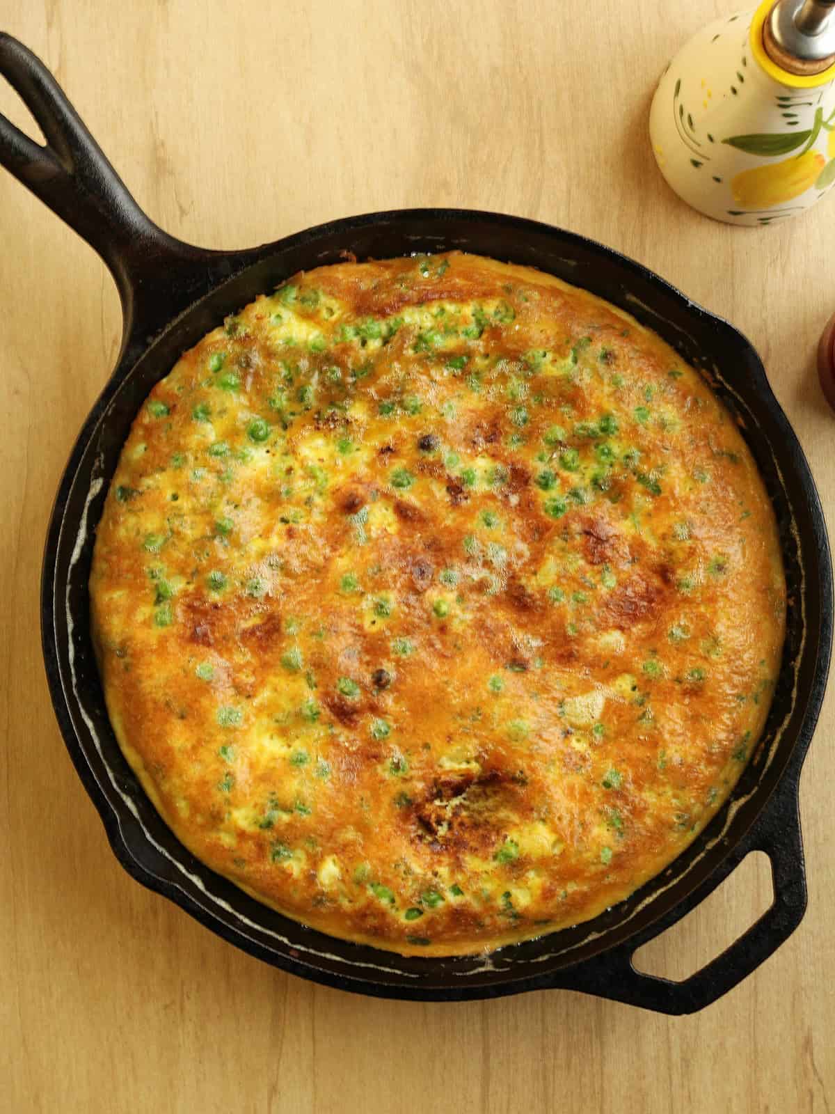 Baked Italian frittata with peas in cast iron skillet.