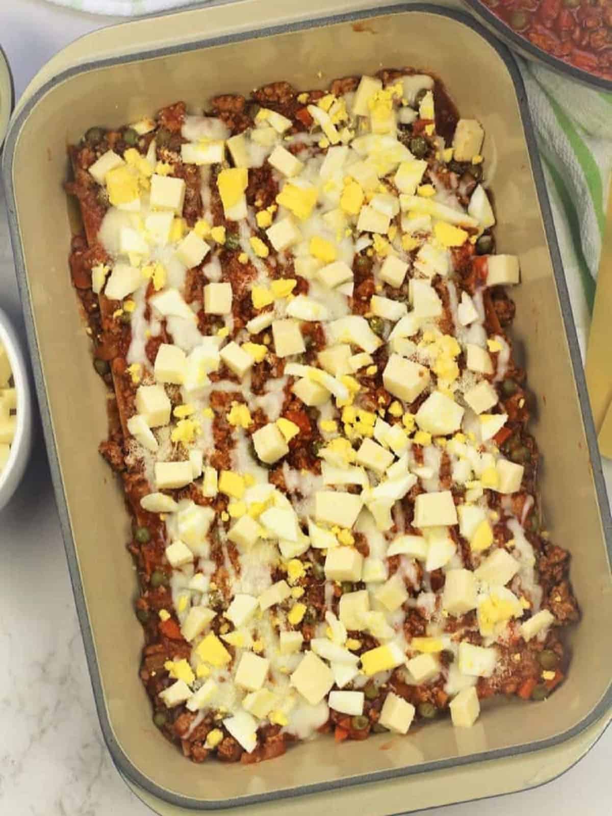 Lasagna layered with hard boiled eggs, mozzarella, béchamel sauce and meat sauce.