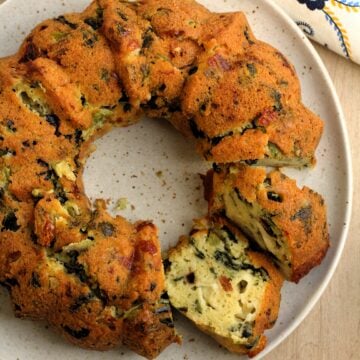 Savory bread ring cake on plate with slices cut.