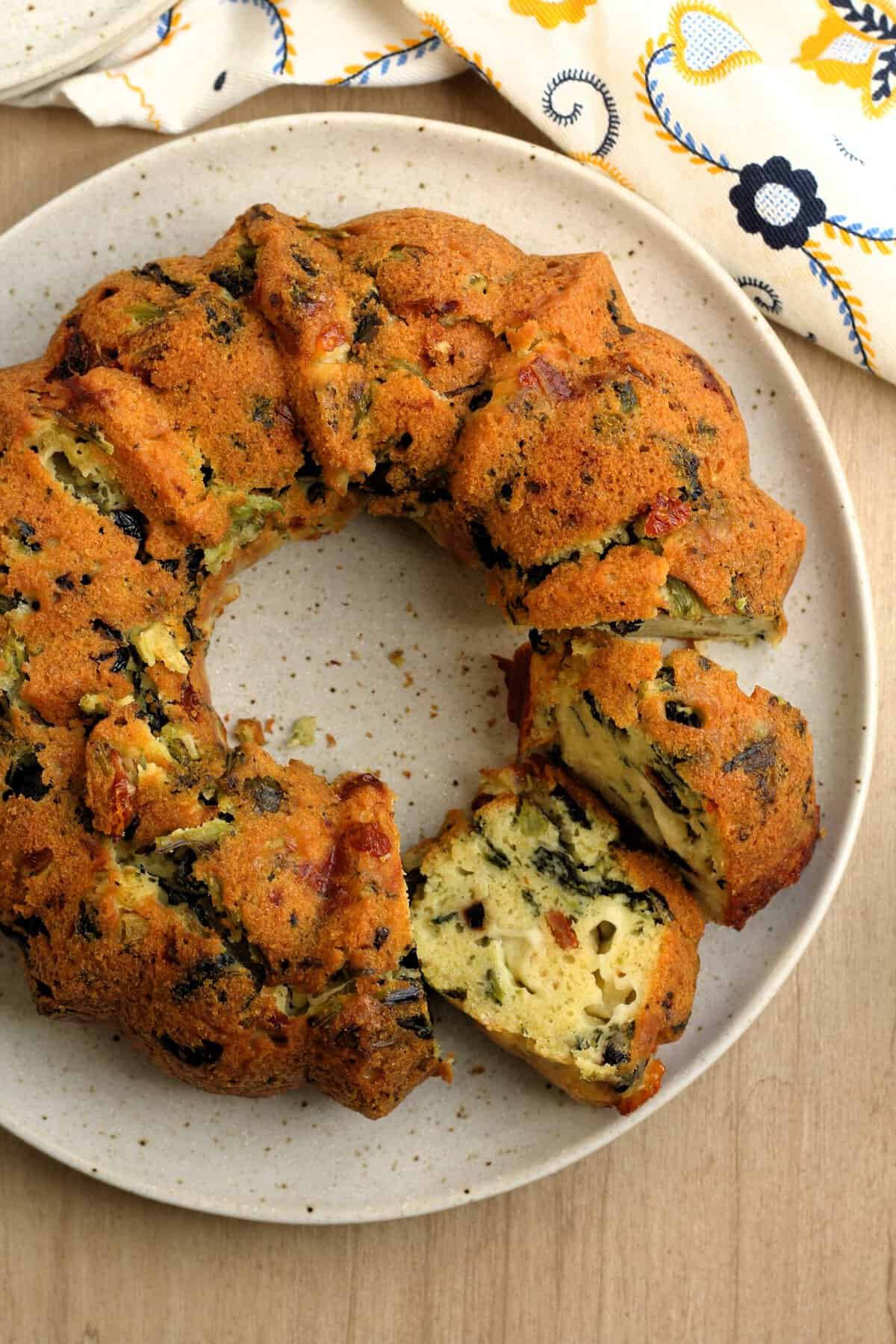 Savory bread ring cake on plate with slices cut.
