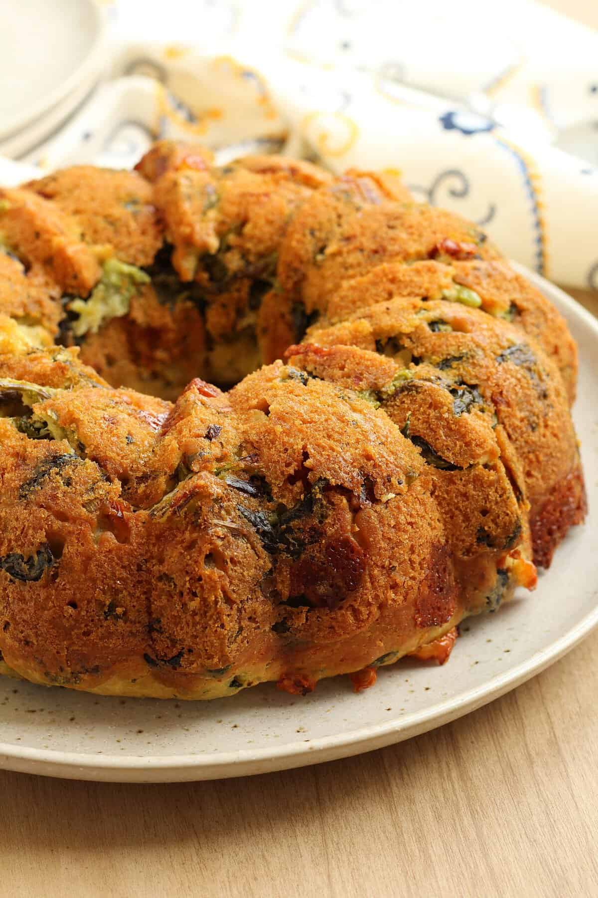 Savory bread ring cake filled with rapini, cheese, sun dried tomatoes and black olives.