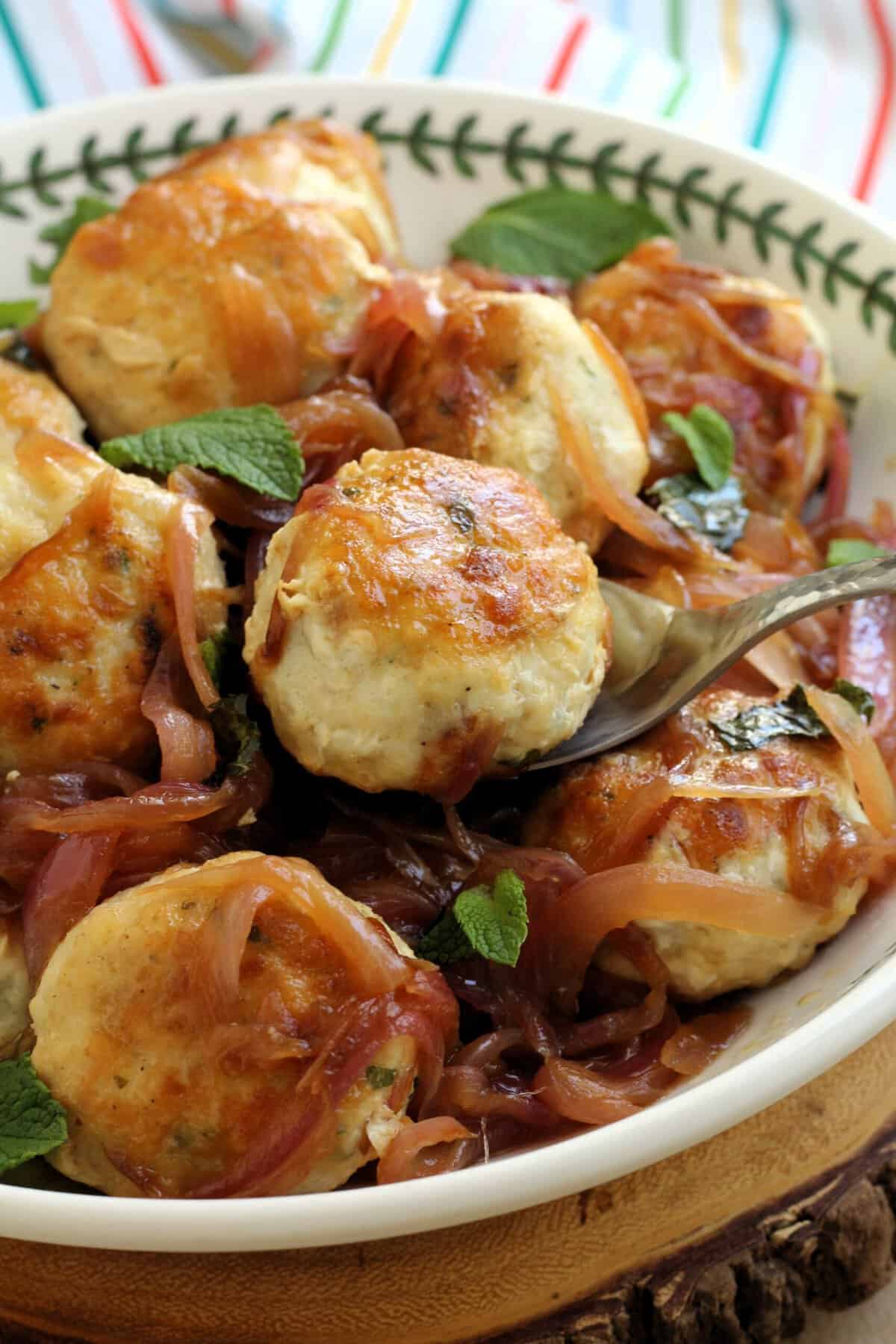 Swordfish meatballs in Sicilian sweet and sour sauce with mint in bowl.