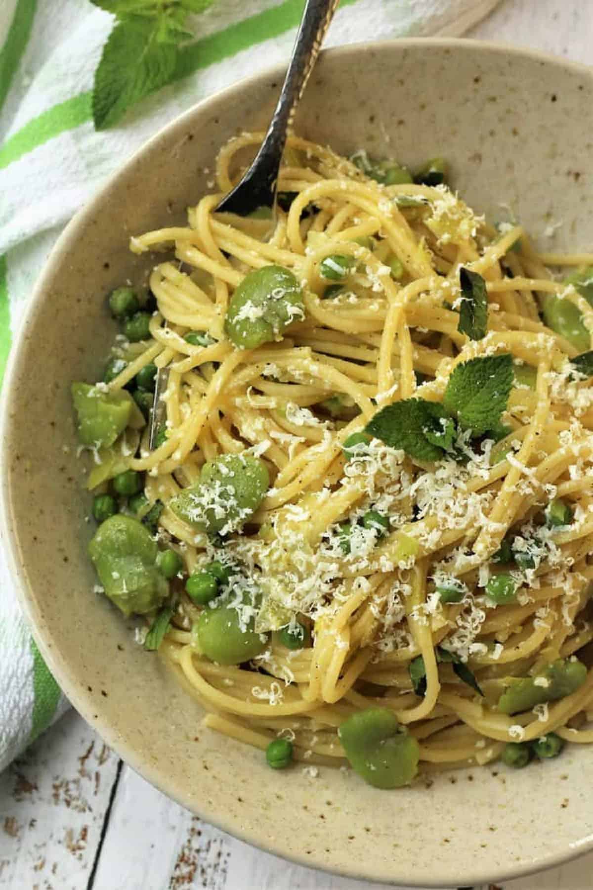 Spaghetti with fava beans, peas and mint topped with grated ricotta salata.
