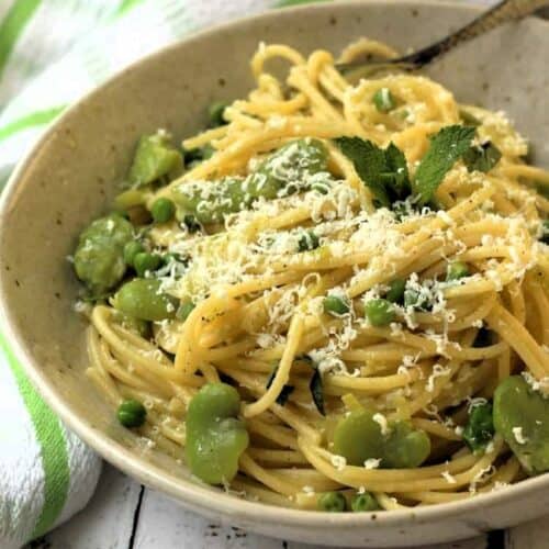 Bowl of pasta with fava beans and peas topped with grated ricotta salata.