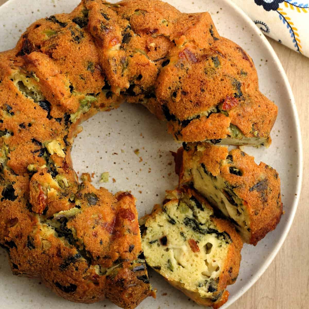 Savory bread ring filled with rapini cut open on plate.