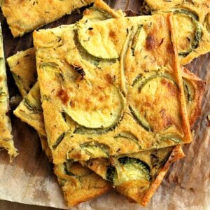 Chickpea flour flatbread with zucchini and onions cut into squres.