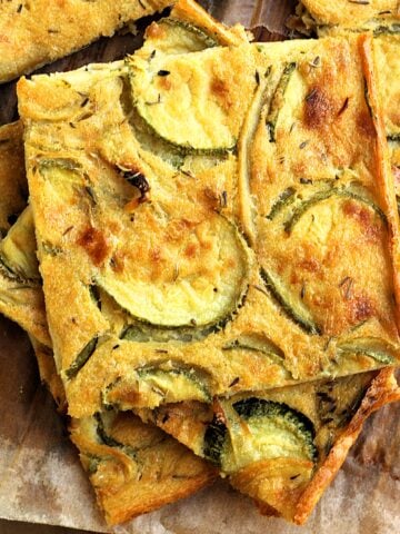 Chickpea flour flatbread with zucchini and onions cut into squres.