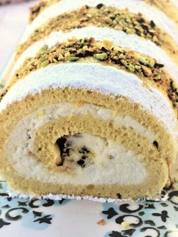 Roll cake filled with ricotta cream and topped with chopped pistachios.