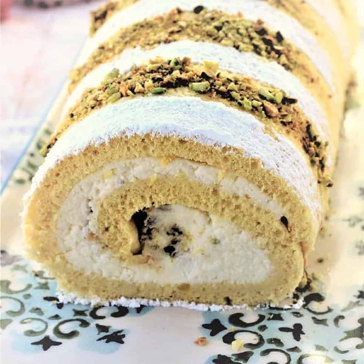 Roll cake filled with ricotta cream and topped with chopped pistachios.
