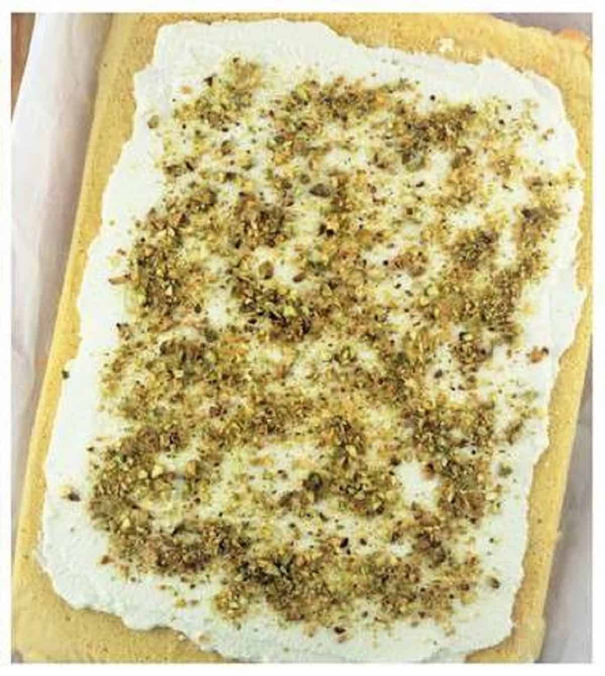 Cake roll covered with ricotta cream and pistachios.