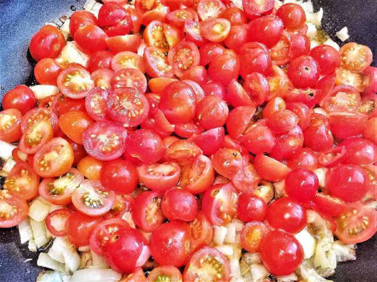 Sautéed cherry tomatoes and onions in a skillet.