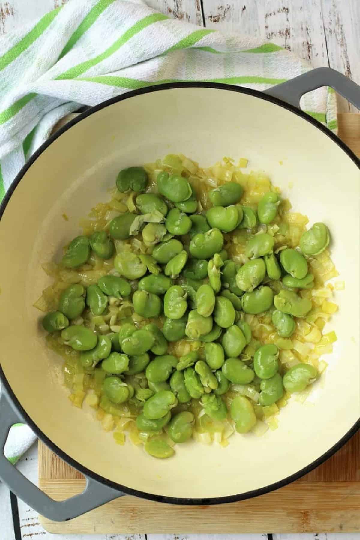 Fava beans added to skillet with sautéed leek.