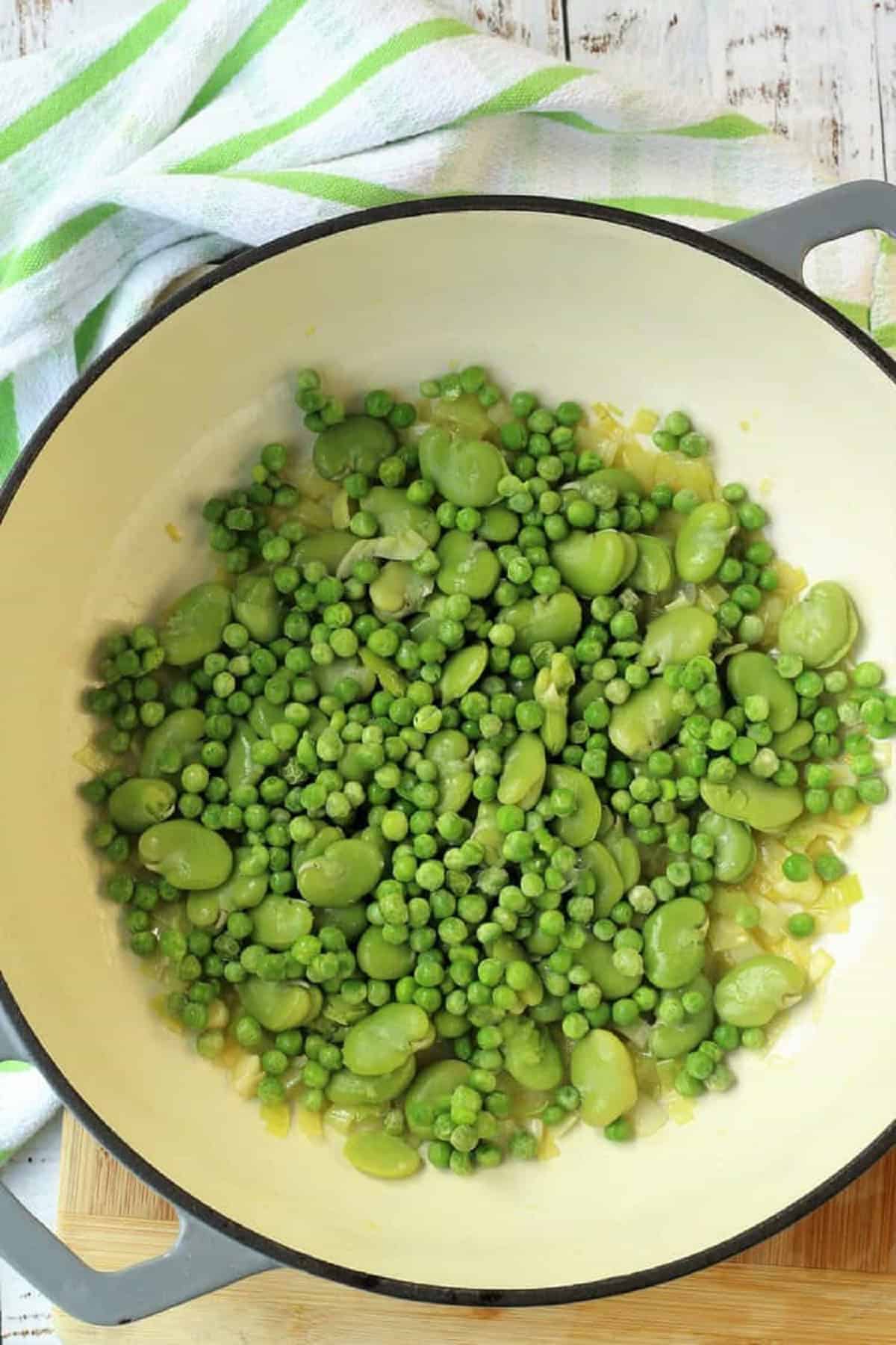Peas and fava beans in skillet with sautéed leek.