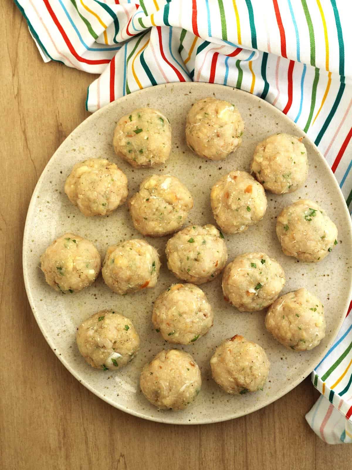 Swordfish meatball mixture rolled into balls on plate.
