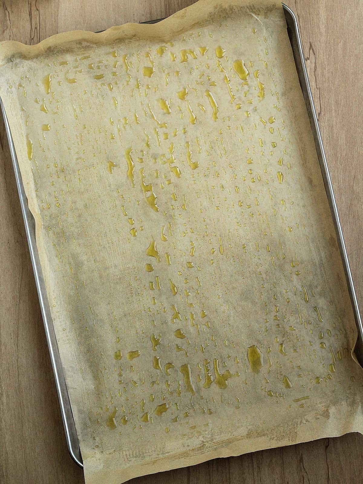 Sheet pan lined with greased parchment paper for chickpea flour flatbread recipe.