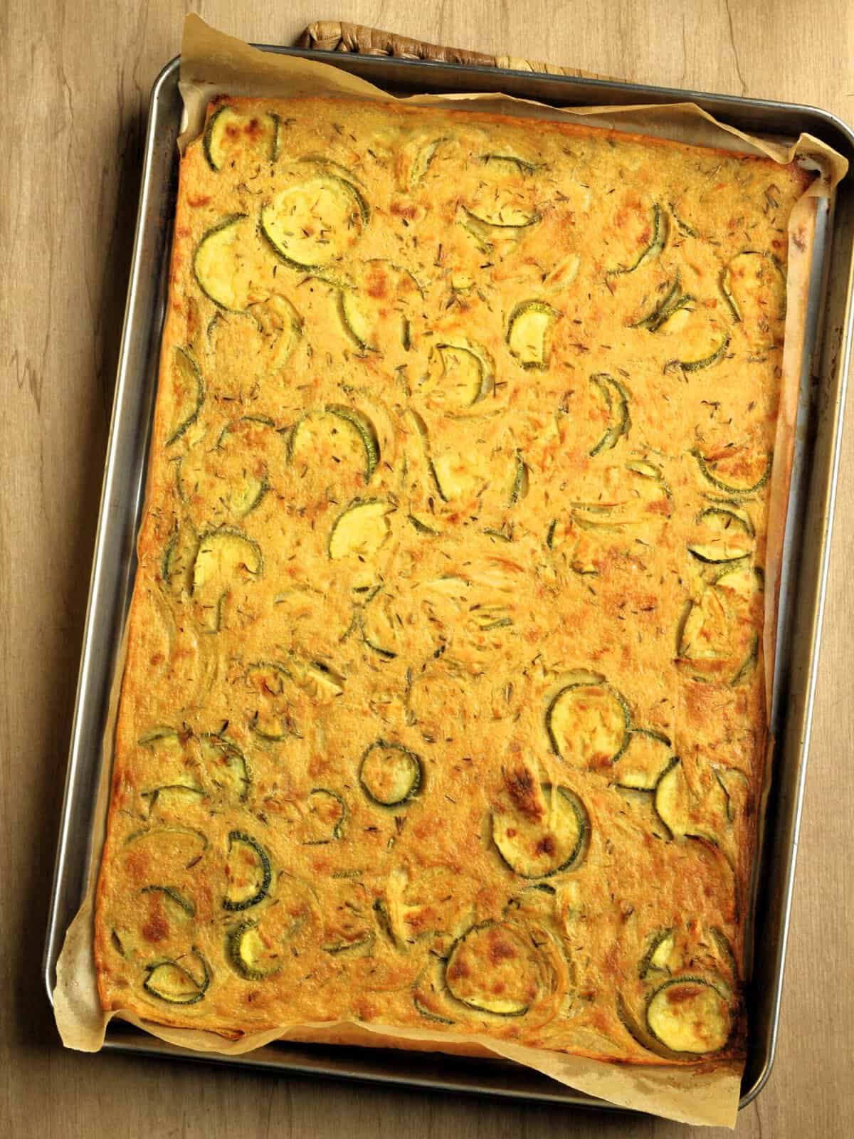 Baked farinata with zucchini and onions in sheet pan.