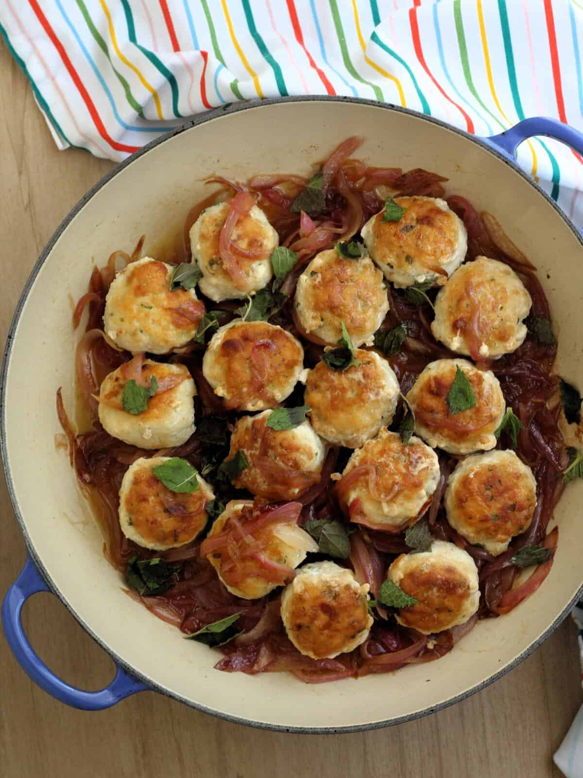 Swordfish meatballs in skillet with sautéed onions in sweet and sour sauce.