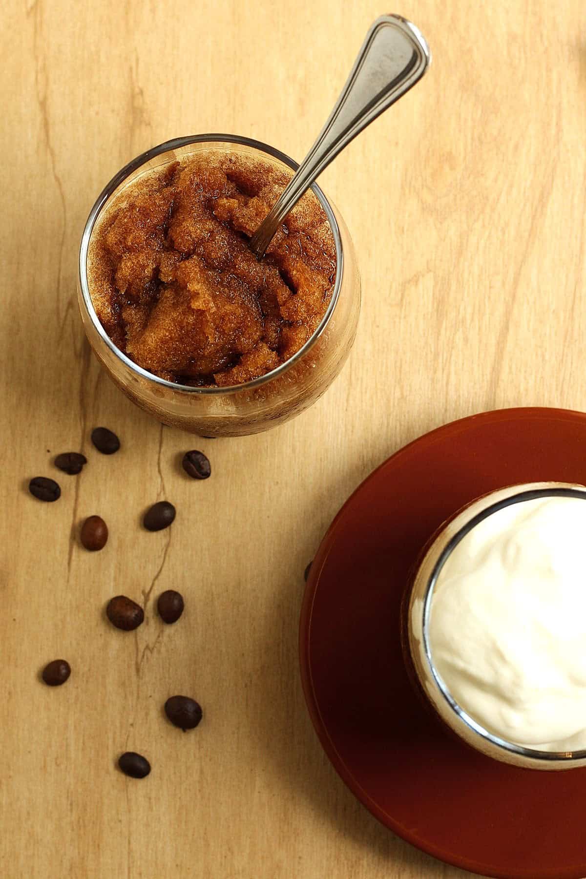 Coffee granita in glass with spoon in it, second glass of granita topped with whipped cream.