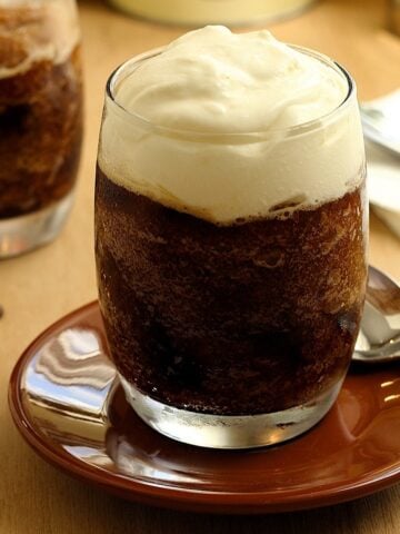 Sicilian granita al caffè con panna in glass on saucer with spoon.