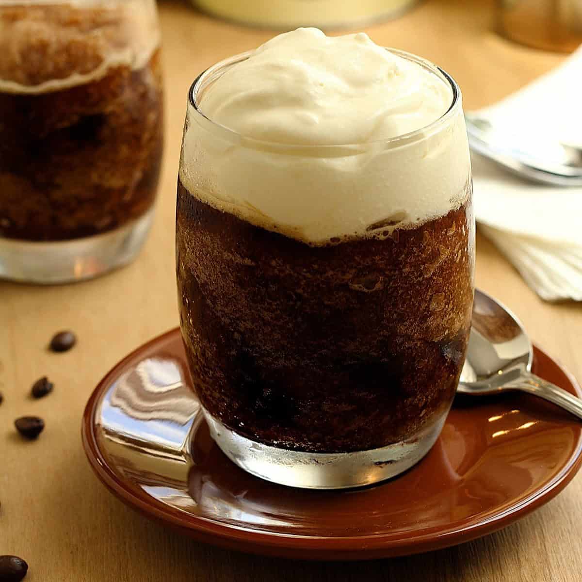Sicilian granita al caffè con panna in glass on saucer with spoon.