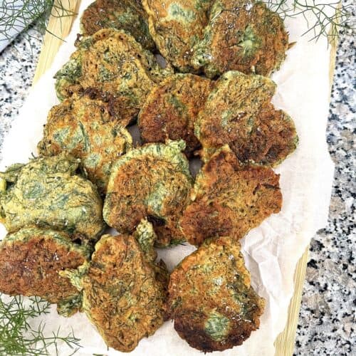 Finocchietto fritters layered on wood board.