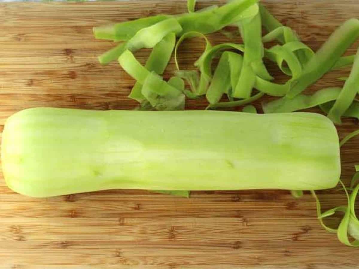 Peeled cucuzza squash on wood board.