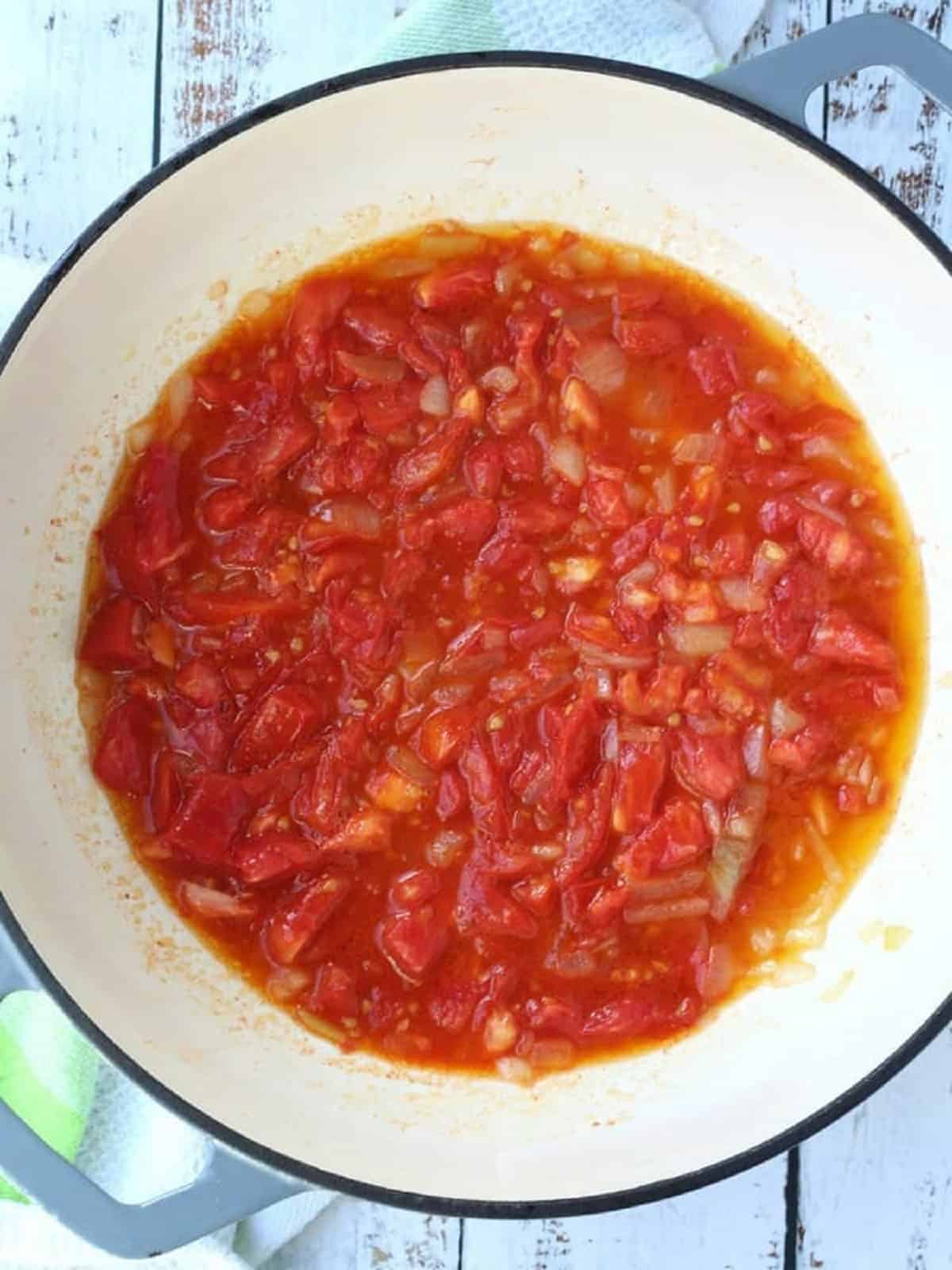 Chopped tomato and onion sautéed in skillet.