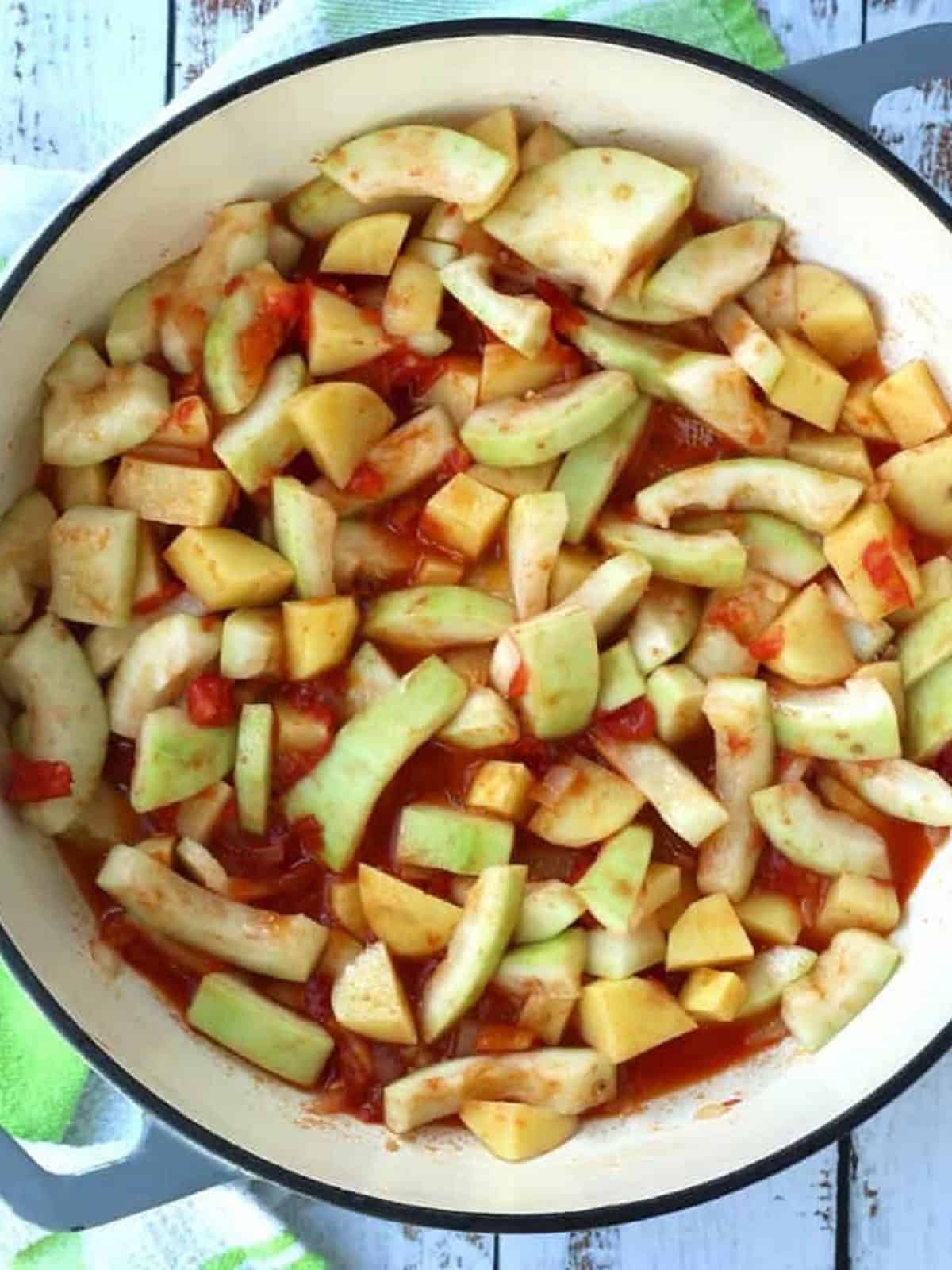 Chopped cucuzza added to skillet with tomato and onion.
