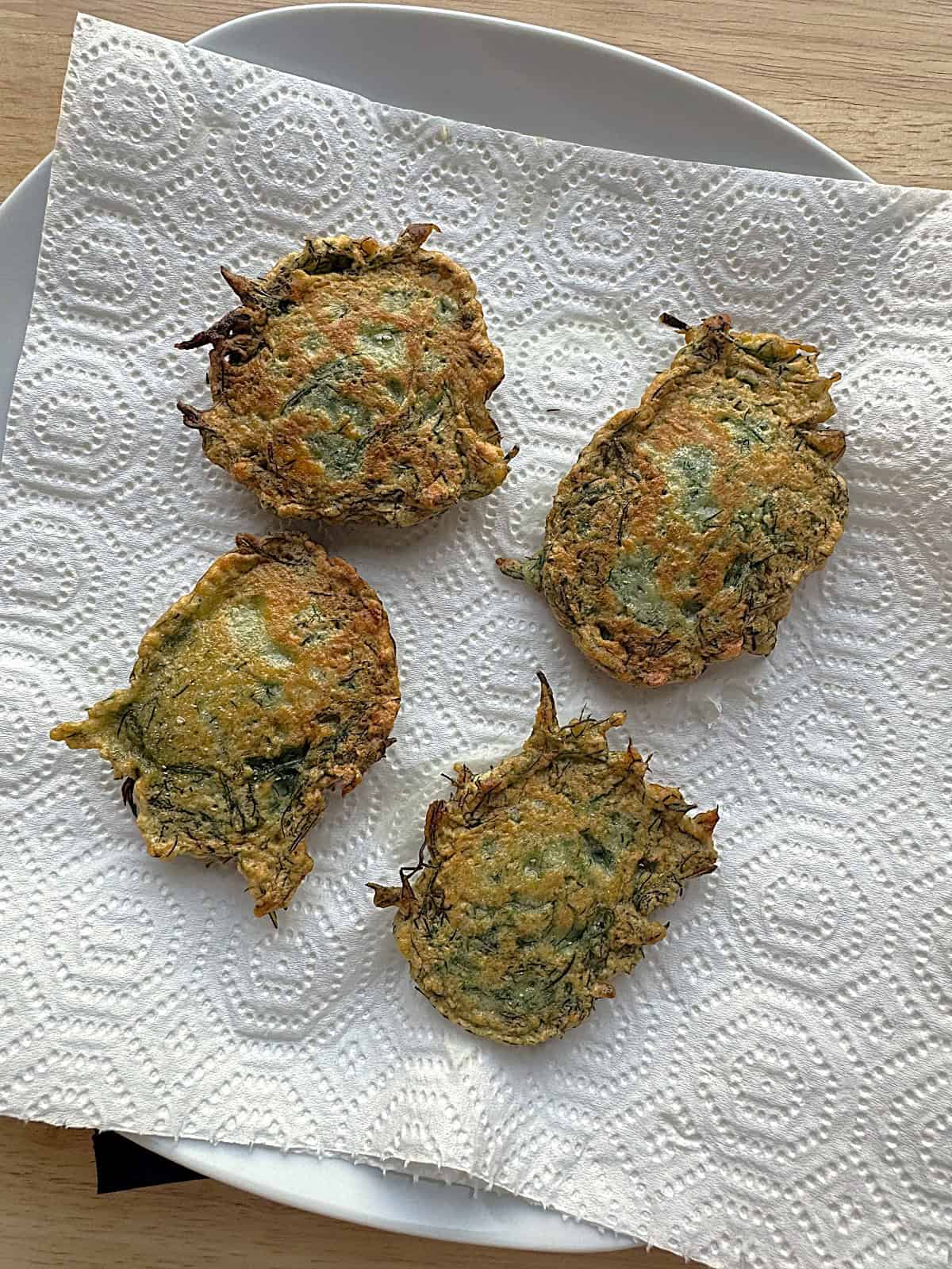 Fried wild fennel fritters on paper towel lined plate.