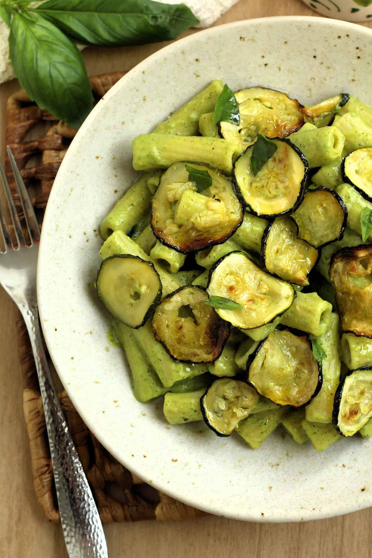 Bowl filled with pasta with zuchini pesto and oven roasted zucchini.