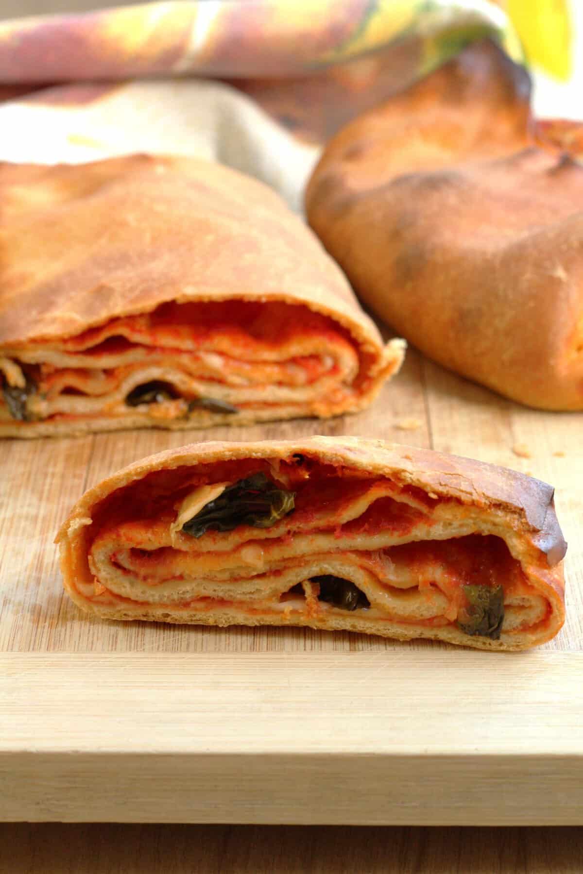 Scaccia Ragusana sliced open to reveal layers of dough, tomato sauce and cheese.