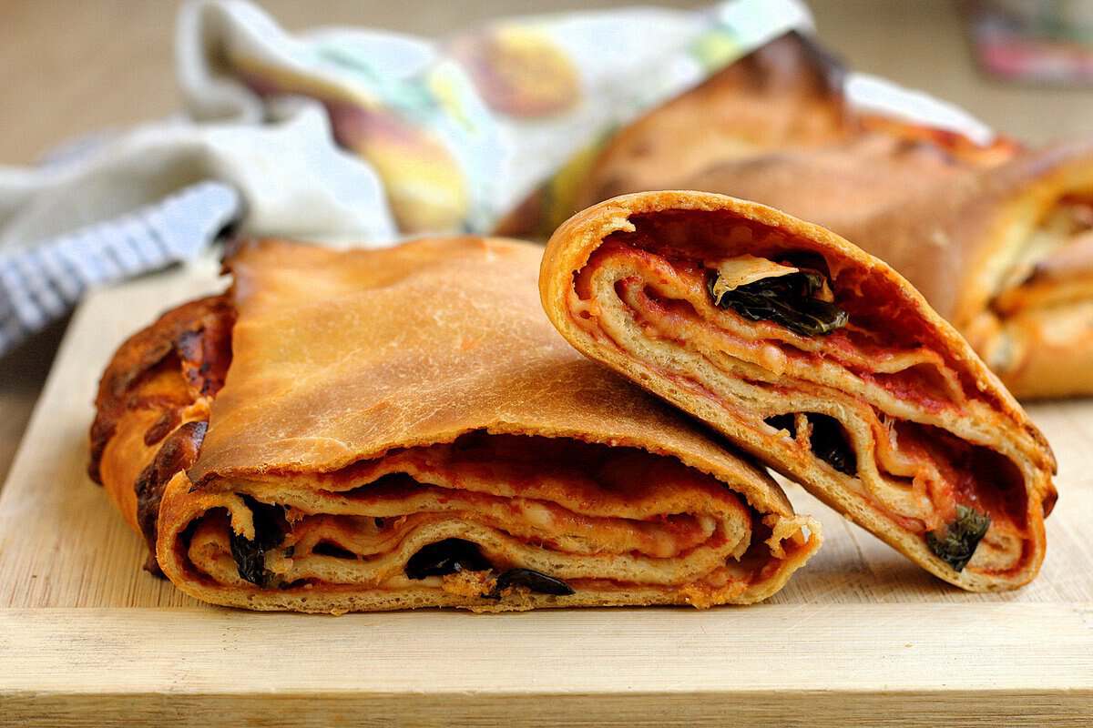 Sicilian scaccia Ragusana sliced open to reveal layers of dough, tomato sauce, and cheese.
