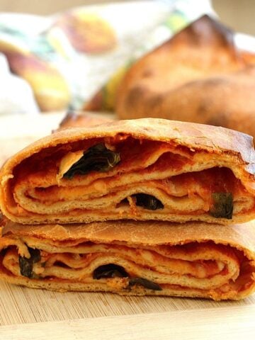 Sicilian scaccia Ragusana bread cut open to revela layers of dough, sauce and cheese.