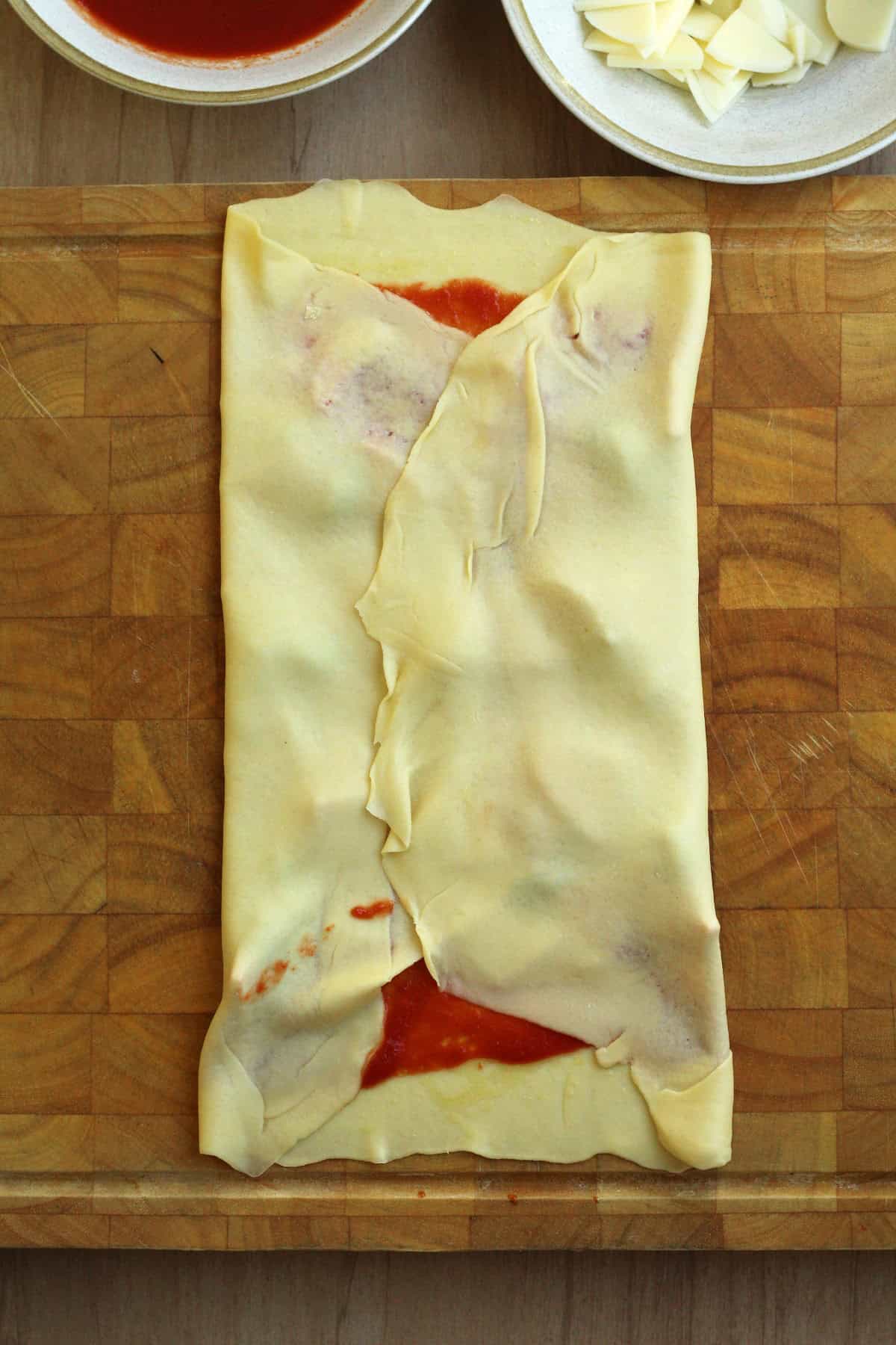 Scaccia al pomodoro dough with two sides folded towards the center.