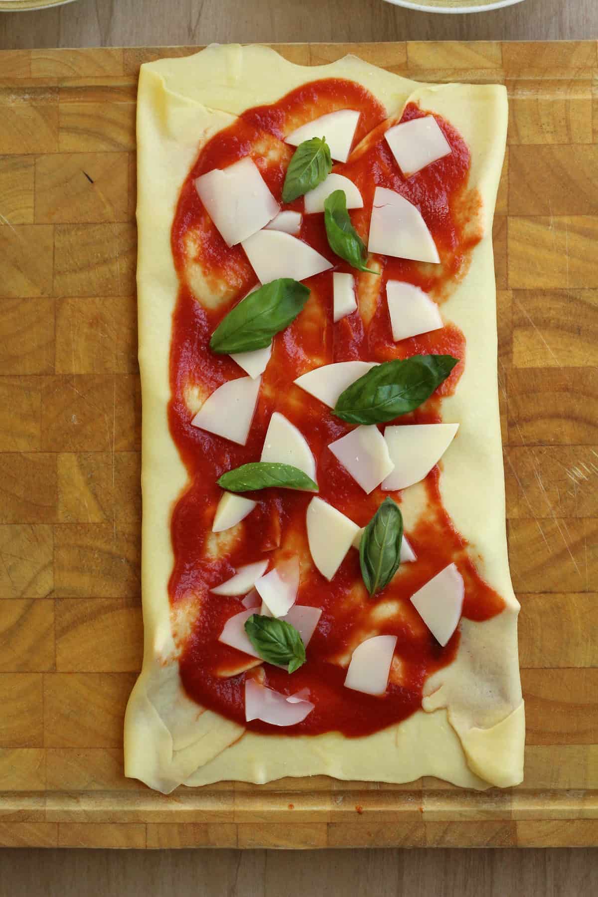 Sicilian scaccia dough topped with tomato sauce, cheese and basil.