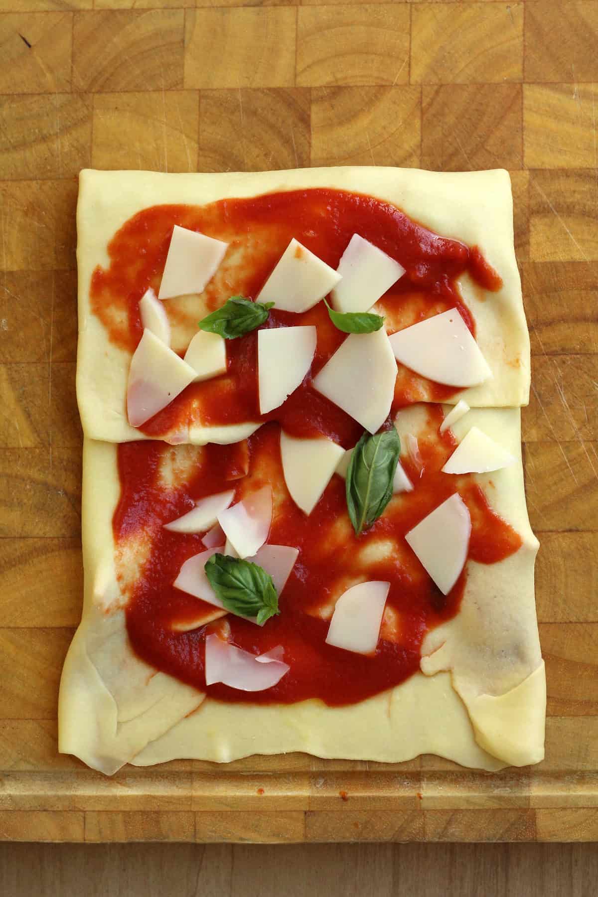 Scaccia dough topped with tomato sauce, cheese and basil , folded over like an envelop.e