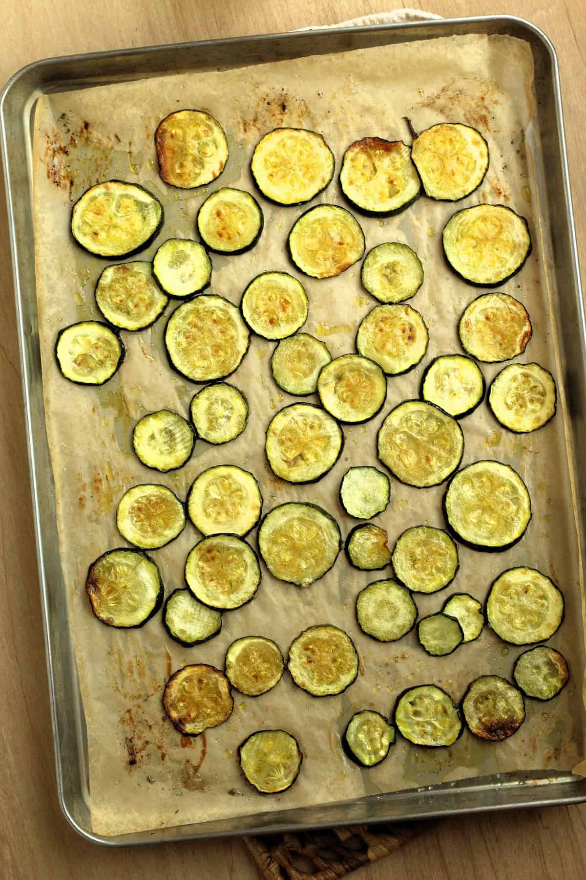 Oven roasted zucchini rounds on baking sheet coated ith olive oil.
