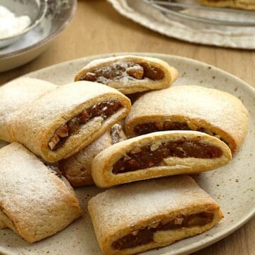 Fig jam cookies (settembrini) dusted with powdered sugar on plate.