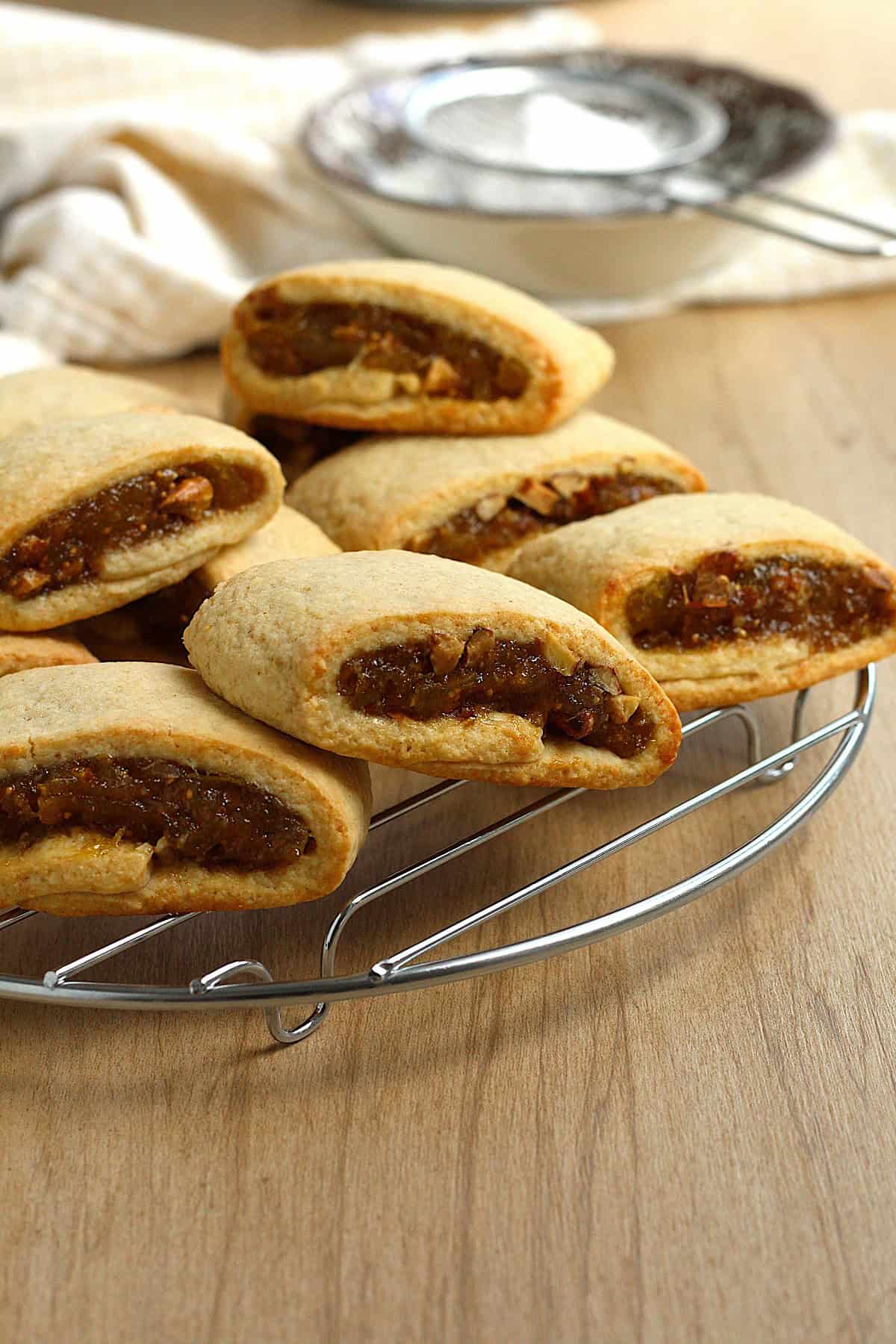 Settembrini (fig cookies) on wire rack next to bowl with powdered sugar and sieve.